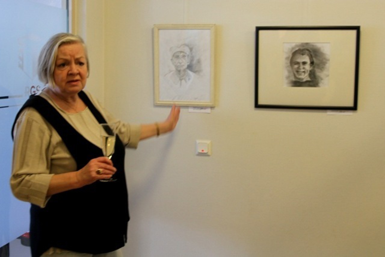 Kursleiterin Frau Breddin vor Porträts der Ausstellung