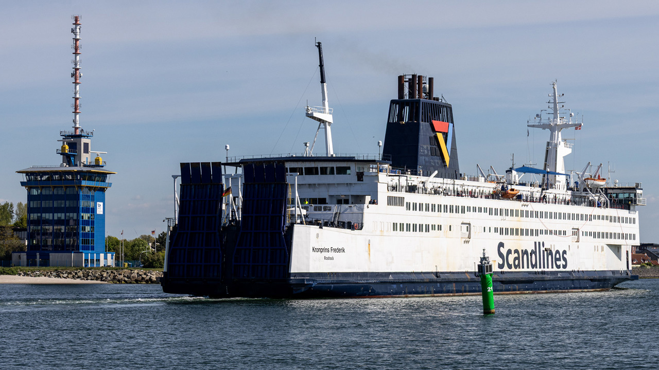 Heckansicht der Fähre „Kronprins Frederik" mit hochgeklappten Heckklappen im Seekanal Warnemünde, links der blaue Turm der Verkehrszentrale.