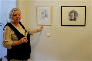 Kursleiterin Frau Breddin vor Porträts der Ausstellung