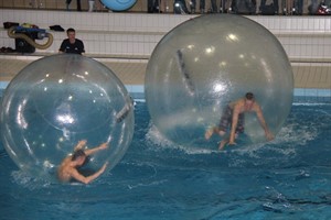 Sportler laufen in Kunststoffbällen übers Wasser