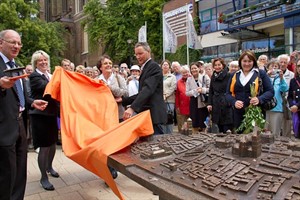 OB Roland Methling, Helga Biemann (Vorstand Volks- und Raiffeisenbank), Gudrun Buse (Blinden- und Sehbehindertenverein MV) und Bildhauer Dirk Wunderlich enthüllen das Bronzerelief der Rostocker Altstadt