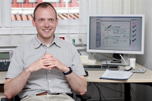 Dr. Hans-Jörg Schulz. Im Hintergrund auf dem Bildschirm ist eine Abbildung von der in Graz entwickelten Software zu sehen.