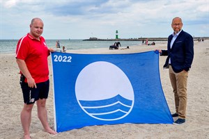 Lukas Knaup (links) vom DRK und Rostocks Tourismusdirektor Matthias Fromm freuen sich über die Verleihung der Blauen Flagge in Warnemünde und Markgrafenheide (Foto: Joachim Kloock)